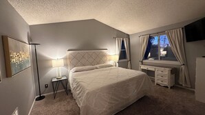 A bedroom with a large bed, bedside tables, a desk, and a window with curtains. - Charming Broomfield Retreat: Modern Comforts & Prime Location
 (Broomfield)