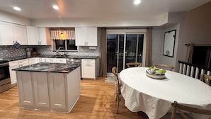 A modern kitchen with white cabinets, a marble island, and a dining area with a white table and chairs. - Charming Broomfield Retreat: Modern Comforts & Prime Location
 (Broomfield)