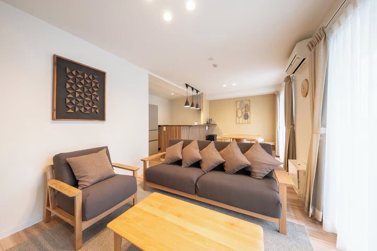 Una sala de estar moderna con un sofá, una mesa de centro de madera y un adorno de pared decorativo.