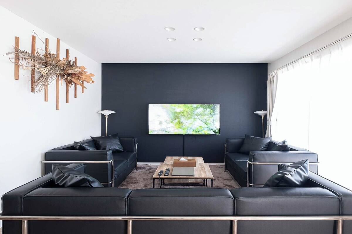 Una sala moderna con un sofá modular, una mesa de centro y un televisor de pantalla plana montado en la pared.
