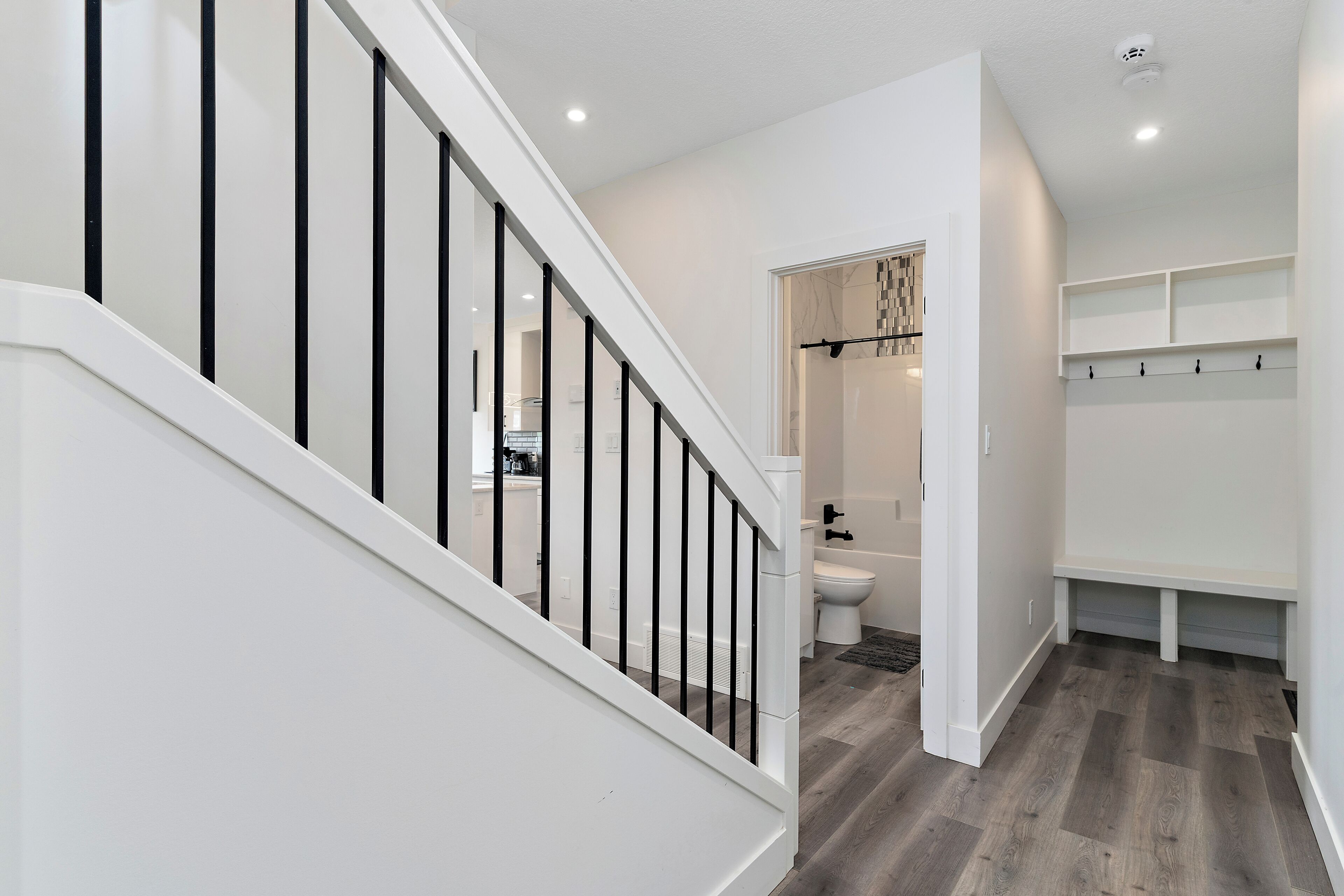 Un interior moderno con una escalera, un baño y un pasillo con estanterías empotradas.