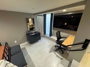 Ein modernes Zimmer mit Esstisch, schwarzem Bürostuhl, dunklem Schminktisch und einem Fenster mit Vorhängen.