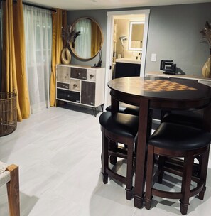 A dining area with a round table, black chairs, a white cabinet, and a mirror. - Midtown 1BR Hideaway: Steps to Ice Blocks (Sacramento)