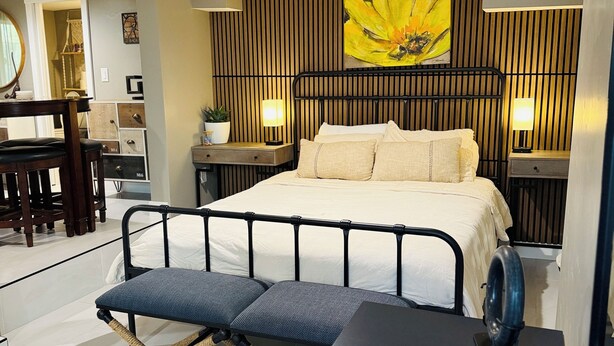 A modern bedroom with a bed, bedside lamps, a desk, and a chair. - Midtown Studio Hideaway: Steps to Ice Blocks (Sacramento)