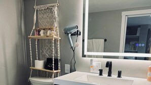 Ein Badezimmer mit Toilette, Waschbecken inklusive Spiegel und einem Handtuchhalter.