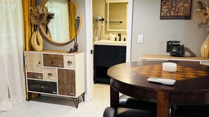 A dining area with a round table and chairs, a cabinet with drawers, a mirror, and a wall-mounted artwork. - Midtown Studio Hideaway: Steps to Ice Blocks (Sacramento)