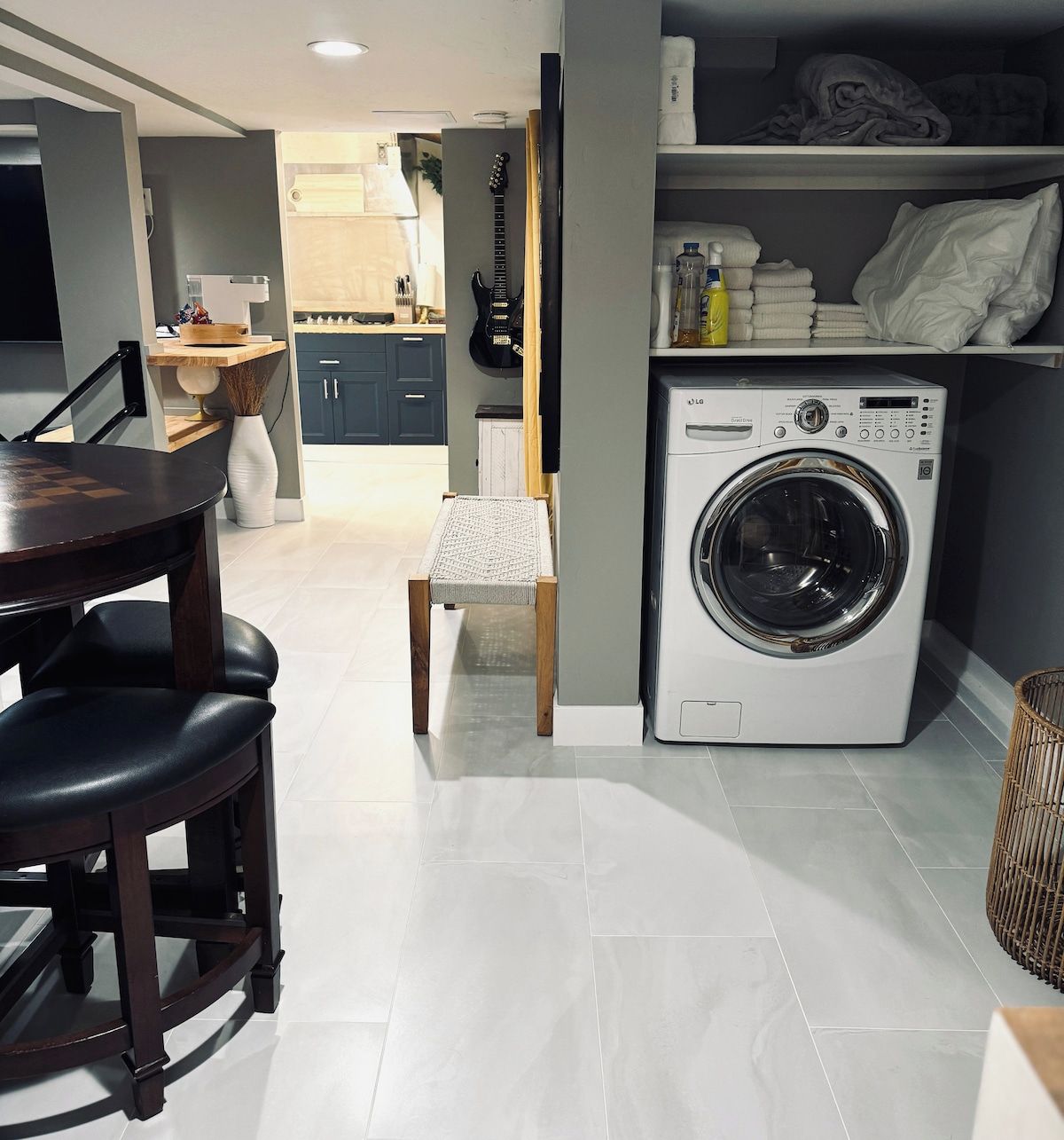 A compact kitchen with a washing machine, a dining table with chairs, and a small seating area.
