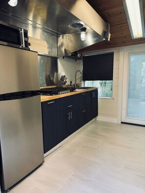 A modern kitchen with stainless steel appliances, a wooden countertop, and a large window with blinds. - Midtown 1BR Hideaway: Steps to Ice Blocks (Sacramento)