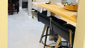 A modern dining area with a wooden table and black chairs, a bed with a white headboard, and a large floral painting on the wall. - Midtown Studio Hideaway: Steps to Ice Blocks (Sacramento)