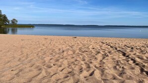 A sandy beach with footprints leading to calm water. - 4 Star Holiday Home in Vingaker (Vingåker)
