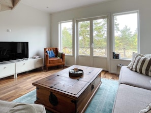 A living room with a television, a wooden coffee table, a sofa, and a chair. - 4 Star Holiday Home in Vaxholm (Vaxholm)