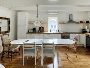 A modern kitchen with a central island, white cabinetry, a chandelier, and a view of the outdoors. - 4 Star Holiday Home in Vaxholm (Vaxholm)