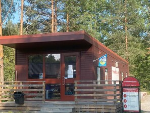 A small wooden building with a red roof, a wooden fence, and a signboard. - 4 Star Holiday Home in Vaxholm (Vaxholm)
