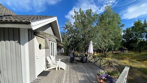 A wooden deck with outdoor furniture, a barbecue grill, and potted plants. - 4 Star Holiday Home in Vaxholm (Vaxholm)