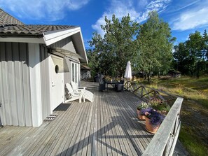A wooden deck with outdoor furniture, a barbecue grill, and potted plants. - 4 Star Holiday Home in Vaxholm (Vaxholm)
