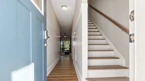 A hallway with a blue door, wooden stairs, and a view into another room. - Ducks Landing Accommodations at Southern Pines Golf Course (Aberdeen)