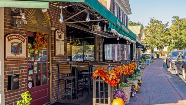 A brick building with a green awning and outdoor seating area. - Ducks Landing Accommodations at Southern Pines Golf Course (Aberdeen)