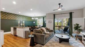 A modern living room with a sofa, coffee table, and dining area. - Ducks Landing Accommodations at Southern Pines Golf Course (Aberdeen)