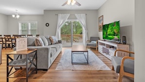A modern living room with a sofa, coffee table, TV, and ceiling fan. - Ducks Landing Accommodations at Southern Pines Golf Course (Aberdeen)
