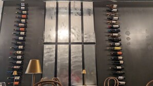 A restaurant interior with a wall of wine bottles arranged in rows, a large window, and a few tables with chairs. - Ducks Landing Accommodations at Southern Pines Golf Course (Aberdeen)