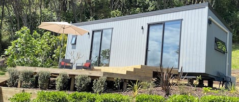 A modern house with a deck, outdoor seating, and a large window.