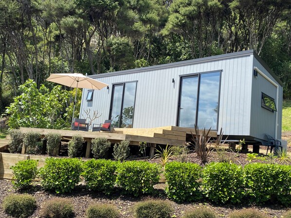 A modern house with a deck, outdoor seating, and a large window.