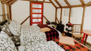 A cozy room with a bed, a red door, a table, and a chair. - Two Queen Beds - All Good in the Woods! (Beaver Bay)
