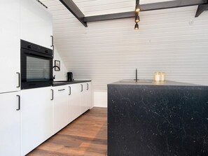 A modern kitchen with white cabinets, a black countertop, and a marble island. - 4 Person Holiday Home in Toftlund (Toftlund)