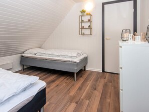 Un dormitorio con cama, cómoda, estante con plantas y una puerta.