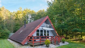 A small, triangular-shaped building with a red roof and white walls, surrounded by a gravel area and greenery. - 4 Person Holiday Home in Toftlund (Toftlund)
