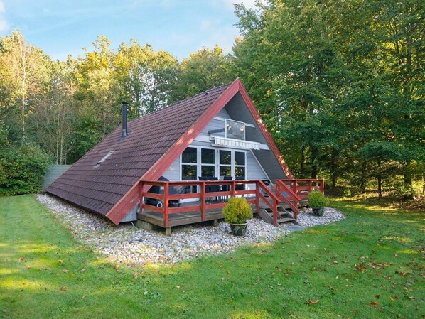 Eine kleine, blockhausartige Hütte mit Holzboden und einem kleinen Garten.