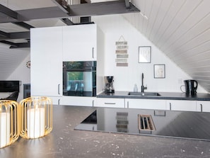 A modern kitchen with white cabinetry, a built-in oven, a coffee maker, and a black countertop. - 4 Person Holiday Home in Toftlund (Toftlund)