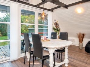 A dining area with a round table, four chairs, and a hanging light fixture.