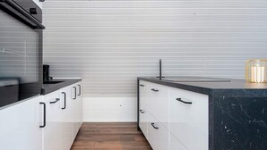 A modern kitchen with white cabinets, black countertops, and a wooden floor. - 4 Person Holiday Home in Toftlund (Toftlund)