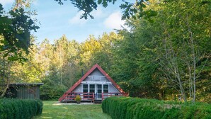 A cabin with a red roof, surrounded by dense greenery and a clear sky. - 4 Person Holiday Home in Toftlund (Toftlund)