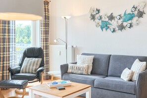 A modern living room with a grey sofa, a black leather armchair, a wooden coffee table, and a floor lamp.