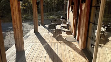 A wooden deck with outdoor seating and a glass door leading to a covered area.