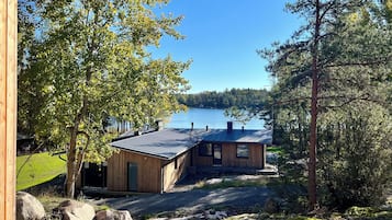 A cabin with a metal roof, wooden walls, and a view of a lake.