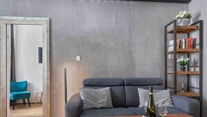 Un salon moderne avec un canapé gris, une table basse en bois et une bibliothèque.
