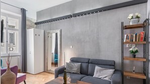 Un salon moderne avec un canapé gris, une table basse en bois et une bibliothèque.
