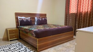 Une chambre à coucher avec un lit en bois, une table de chevet et un tapis à motifs.