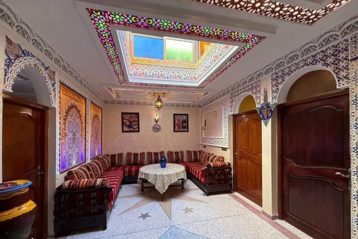 A room with a patterned floor, a central seating area, a wooden door, and a decorative ceiling.