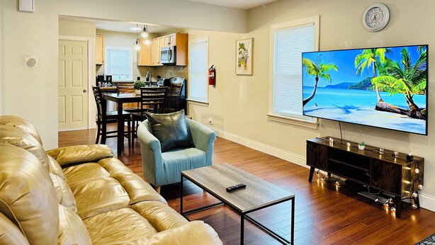 A living room with a leather sofa, a coffee table, a TV, and a ceiling fan. - Campu's Whole House (Cherry Hill)