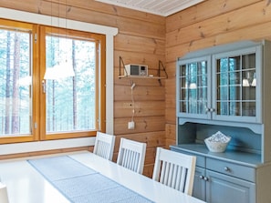 L’intérieur d’une cabine comprenant une table à manger, des chaises, une radio posée sur une étagère et un meuble avec des portes en verre.
