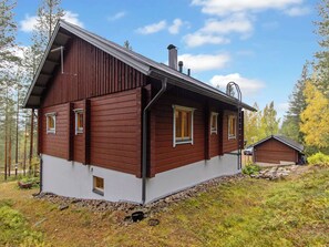 A two-story wooden cabin with a sloped roof, a chimney, and a small attached shed. - Villa uuttu by Interhome (Pelkosenniemi)