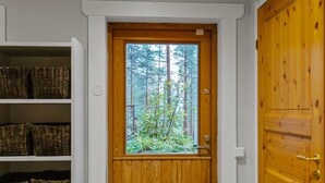 Una puerta de madera con un ventanal, estantes con cestas y un mueble de madera.