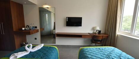 Une chambre d’hôtel avec deux lits, une télévision, un bureau et une fenêtre.