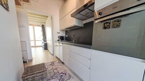 A modern kitchen with white cabinets, stainless steel appliances, and a patterned rug. - Casa di Arianna by Interhome (Noto)