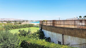 A coastal view with a building featuring a white and brown facade, a garden area with green plants, and a clear blue sky. - Casa di Arianna by Interhome (Noto)