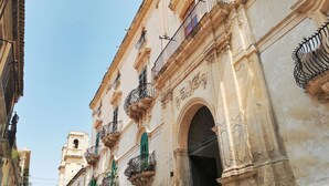 A historic building with ornate balconies and a large arched doorway. - Casa di Arianna by Interhome (Noto)